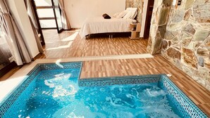 A bedroom with a stone wall, a wooden floor, and a bed with a white bedspread. - Palmar San Gil  (San Gil)