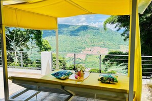 A balcony with a yellow canopy, a table with a bucket, and a view of a green landscape with hills. - Palmar San Gil  (San Gil)