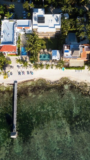 An aerial view of a resort with a beach, pool, and multiple buildings.