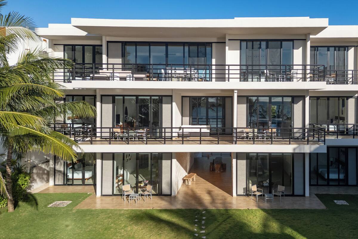 A modern multi-story building with large windows, outdoor seating, and a well-maintained lawn.