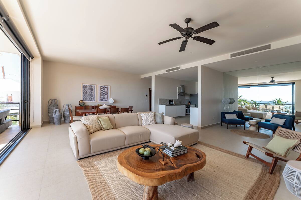 A spacious living area with a large sofa, a wooden coffee table, and a ceiling fan.