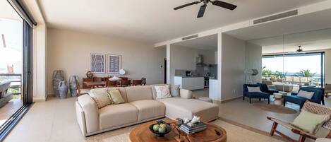A spacious living area with a large sofa, a wooden coffee table, and a ceiling fan.