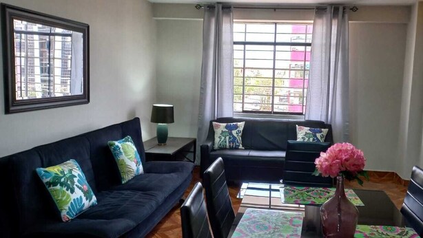 Una sala de estar con un sofá, una mesa de centro y un florero con flores.