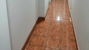 Un pasillo estrecho con paredes blancas y piso de baldosas.