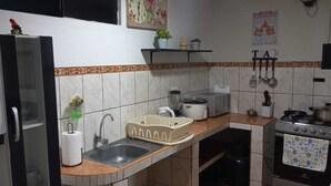 Una cocina compacta equipada con refrigerador, lavamanos, estufa y diferentes utensilios.