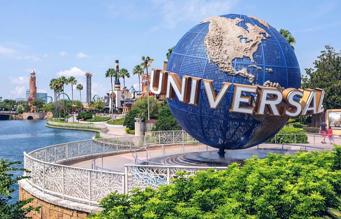 A large blue globe with "UNIVERSAL" written on it, surrounded by a decorative fence and greenery.