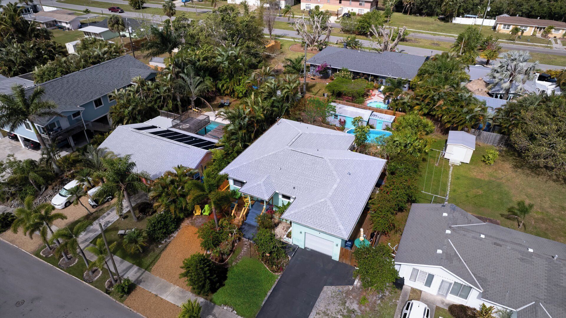 A residential area with houses, a swimming pool, and palm trees.