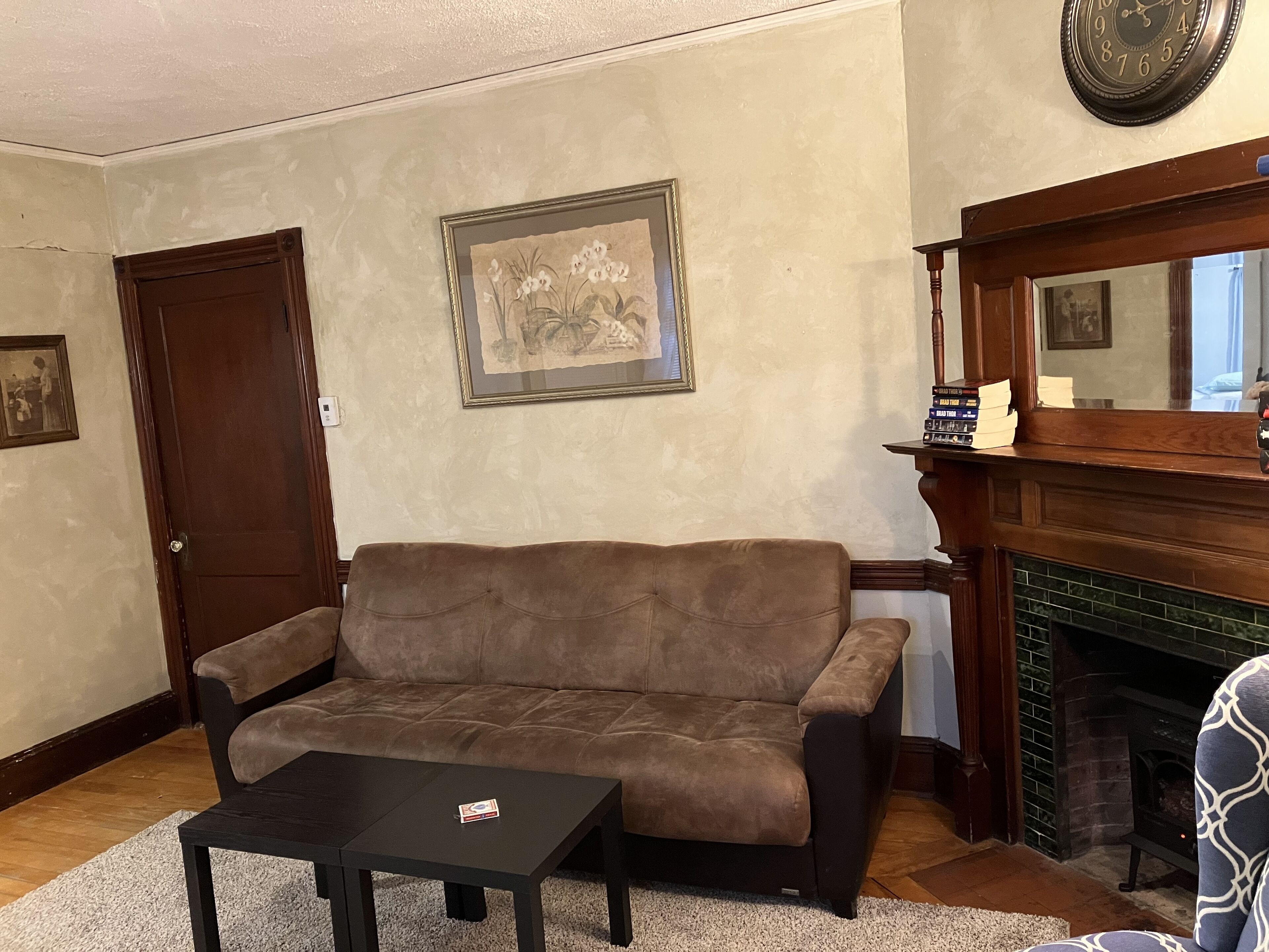 A living room with a brown sofa, a black coffee table, a fireplace, and a framed picture on the wall.