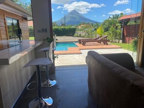 A modern outdoor area with a pool, bar stools, and a sofa. - Magnalia Vacation Home (La Fortuna)