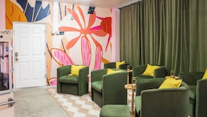 Una habitación con sillones verdes, un tapete estampado y un mural abstracto y colorido en la pared.