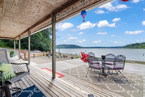 Une terrasse couverte avec des sièges d’extérieur, une vue sur un lac et une montgolfière dans le ciel.