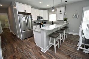 A modern kitchen with white cabinets, stainless steel appliances, and a granite countertop. - 99 Steps to the Beach in Garden City Beach (Garden City Beach)