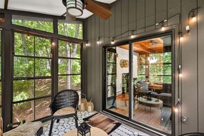 A room with large windows, a ceiling fan, and a view of the outdoors. - Pocono cabin where the host thought of everything, so you don’t have to! (Bushkill)