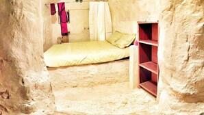 Une petite pièce agréable, avec un lit, une étagère et un rideau.