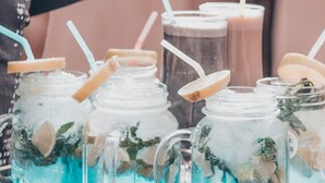 Une table sur laquelle se trouvent plusieurs bocaux en verre remplis de boissons, chacun étant muni d’une paille et d’une tranche de citron.