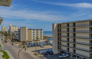 Un hotel de varios pisos con balcones, estacionamiento y vista a la playa.