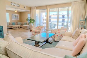 Un salon comprenant un canapé, des fauteuils, une table basse et un balcon avec vue.