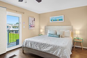 Une chambre à coucher avec un lit, une table de chevet, une fenêtre donnant sur un beau paysage et un ventilateur de plafond.