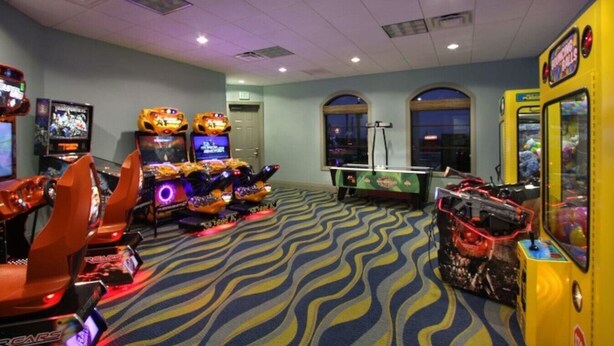 A room with arcade games, a pool table, and a view of the city through large windows. - Amazing 3 bedrooms condo in Resort with Water Park (Davenport)