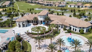 A resort with a central courtyard, a swimming pool, and a golf course in the background. - Amazing 3 bedrooms condo in Resort with Water Park (Davenport)