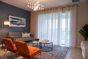 A modern living room with a sofa, two armchairs, a coffee table, and a chandelier.