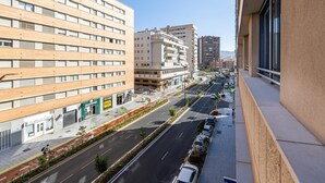 A multi-story building with a modern design, featuring a ground floor with commercial spaces and a street view with parked cars and a cyclist. - Holidays2Malaga Eslava in a closed Urbanization (Málaga)