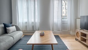 A modern living room with a grey sofa, a wooden coffee table, and a TV on a wooden stand. - Trendy Prenzlauer Berg 1BR, nr Mauerpark, by Blueground (Berlin)