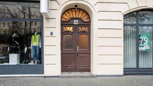 A building with a brown arched entrance door labeled '85', a shop window with mannequins, and a green sign with a gift icon and '75€ BONUS'. - Trendy Prenzlauer Berg 1BR, nr Mauerpark, by Blueground (Berlin)
