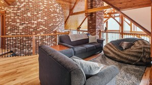 Un acogedor espacio tipo loft con chimenea de ladrillo, vigas de madera y vistas al exterior.