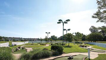 A landscaped park area with pathways, benches, and street lamps.