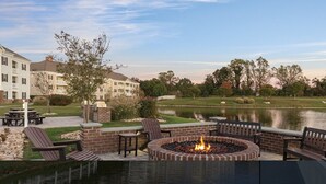 Une terrasse au bord du lac, dotée d’un foyer extérieur, de sièges et offrant une vue sur un terrain de golf.