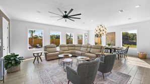 A spacious living room with a sectional sofa, a dining area, and a ceiling fan. - Fall is Near and the Most Wonderful time of year! (Panama City Beach)