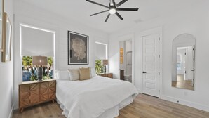 A spacious bedroom with a large bed, a ceiling fan, and a view of the outdoors. - Fall is Near and the Most Wonderful time of year! (Panama City Beach)