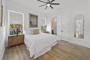 A spacious bedroom with a large bed, a ceiling fan, and a view of the outdoors. - Fall is Near and the Most Wonderful time of year! (Panama City Beach)