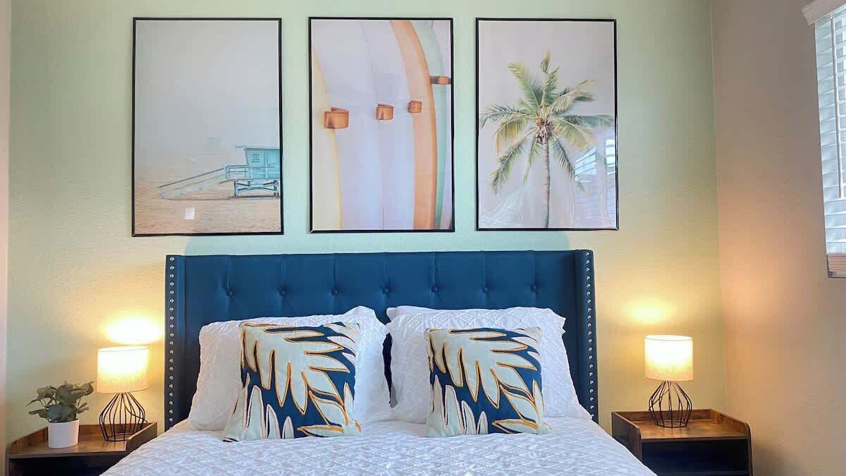 A bedroom with a large bed, two bedside tables with lamps, and three framed pictures on the wall.