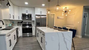 A modern kitchen with white cabinetry, stainless steel appliances, a marble island, and pendant lighting. - *Moonlight Cinema* - 15 min to Legoland! (Vista)