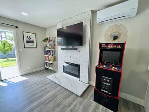 A modern living room with a flat-screen TV, a fireplace, and a video game console.