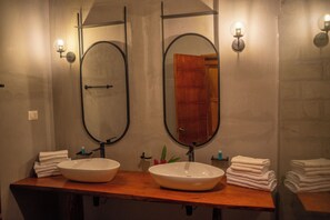 A bathroom with two sinks, a wooden countertop, and two wall-mounted mirrors.