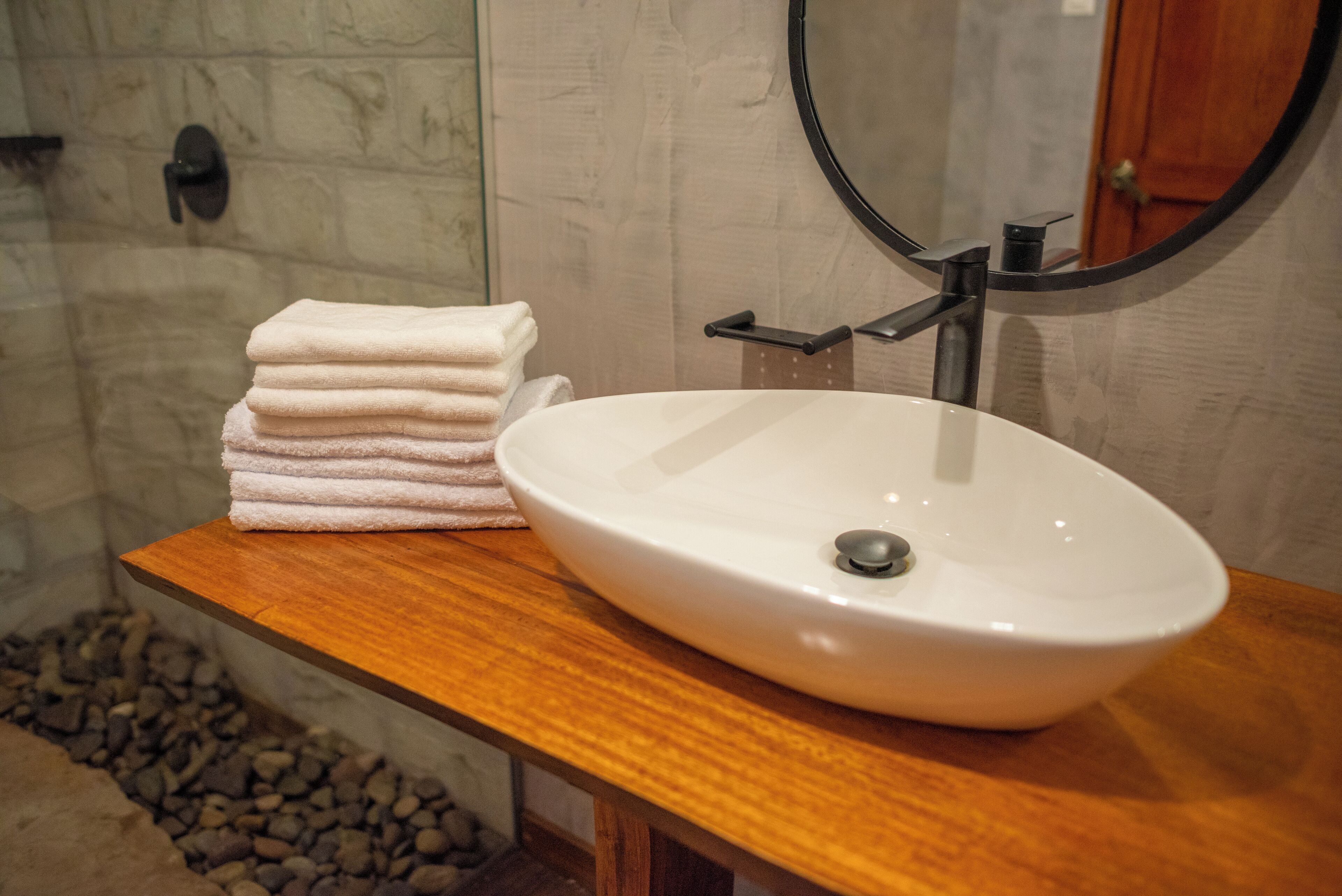 Un baño con un lavamanos blanco, una encimera de madera y una pila de toallas.