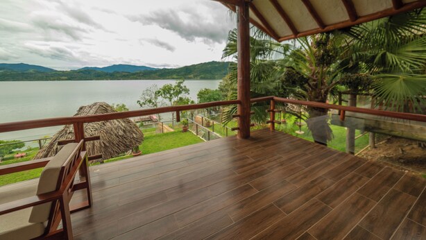 Una terraza de madera con vista a un lago y montañas.