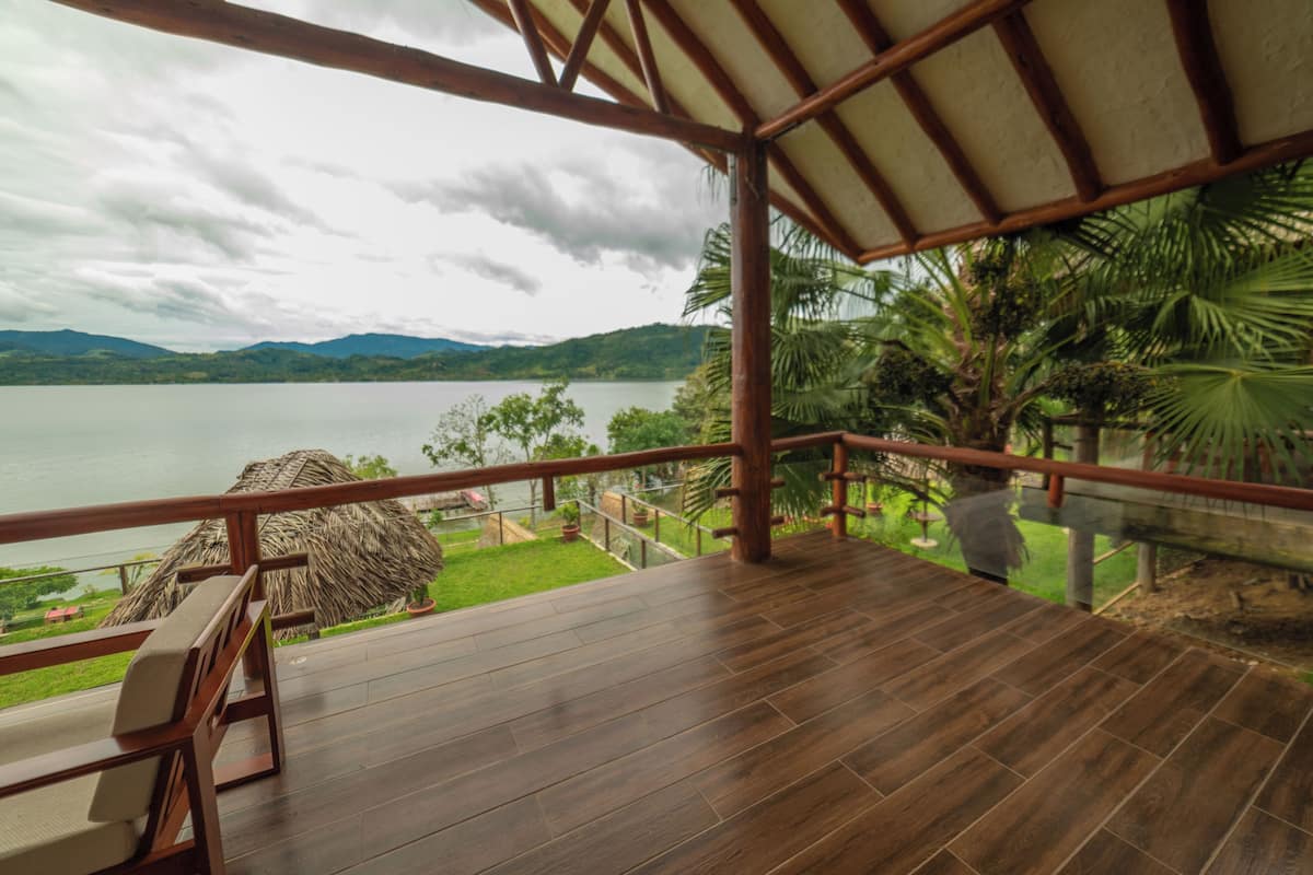 Una terraza de madera con vista a un lago y montañas.