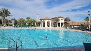 A swimming pool with clear lanes, surrounded by lounge chairs and palm trees.