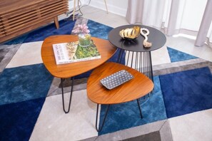 A room with a blue and white patterned carpet, a wooden coffee table with a magazine, a small round table with a decorative item, and a wooden sideboard. - 4BR ChampionsGate Private Pool Lazy River Access (Davenport)