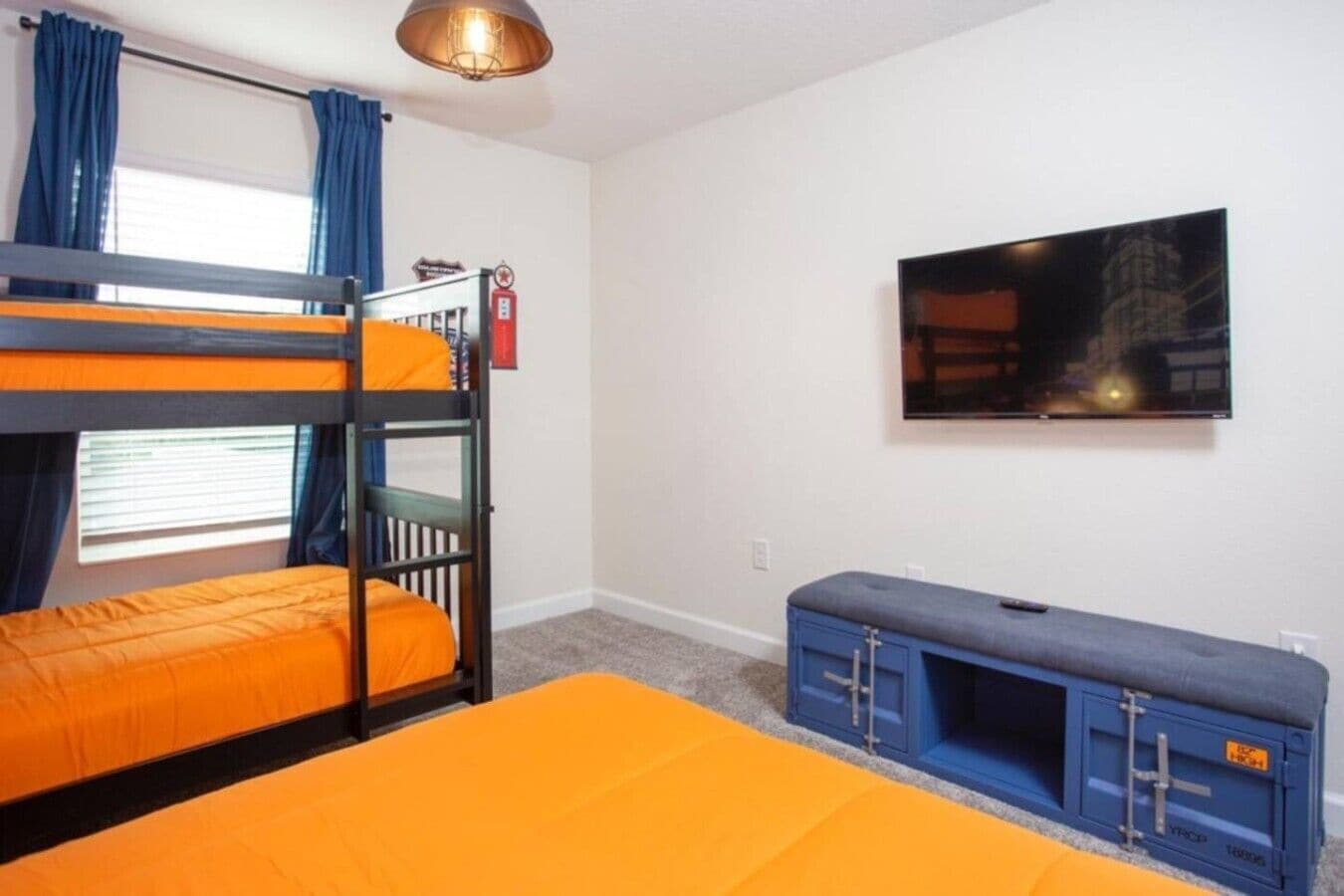 A room with bunk beds, a television, and a bench.