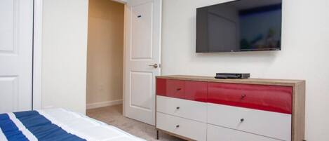 A bedroom with a bed, a TV mounted on the wall, and a dresser with drawers.