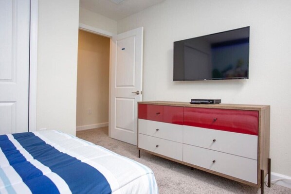 A bedroom with a bed, a TV mounted on the wall, and a dresser with drawers.