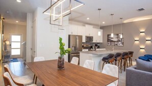 Une cuisine moderne avec des meubles blancs, un îlot central et des luminaires suspendus.
