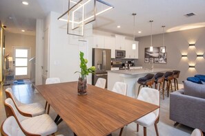 A modern kitchen with white cabinets, a central island, and pendant lighting. - 4BR ChampionsGate Private Pool Lazy River Access (Davenport)
