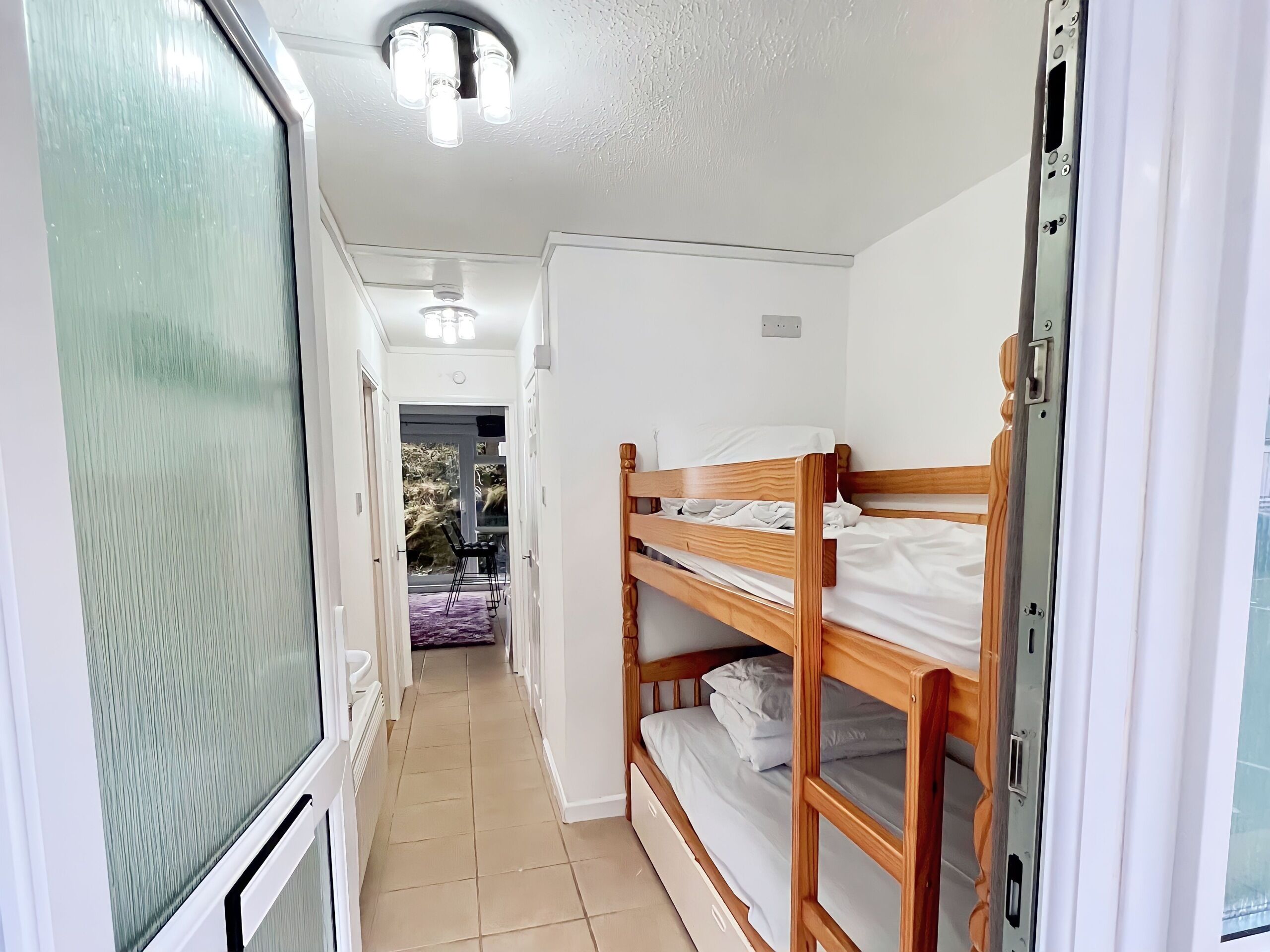 A narrow hallway with a bunk bed and a door leading to a room.
