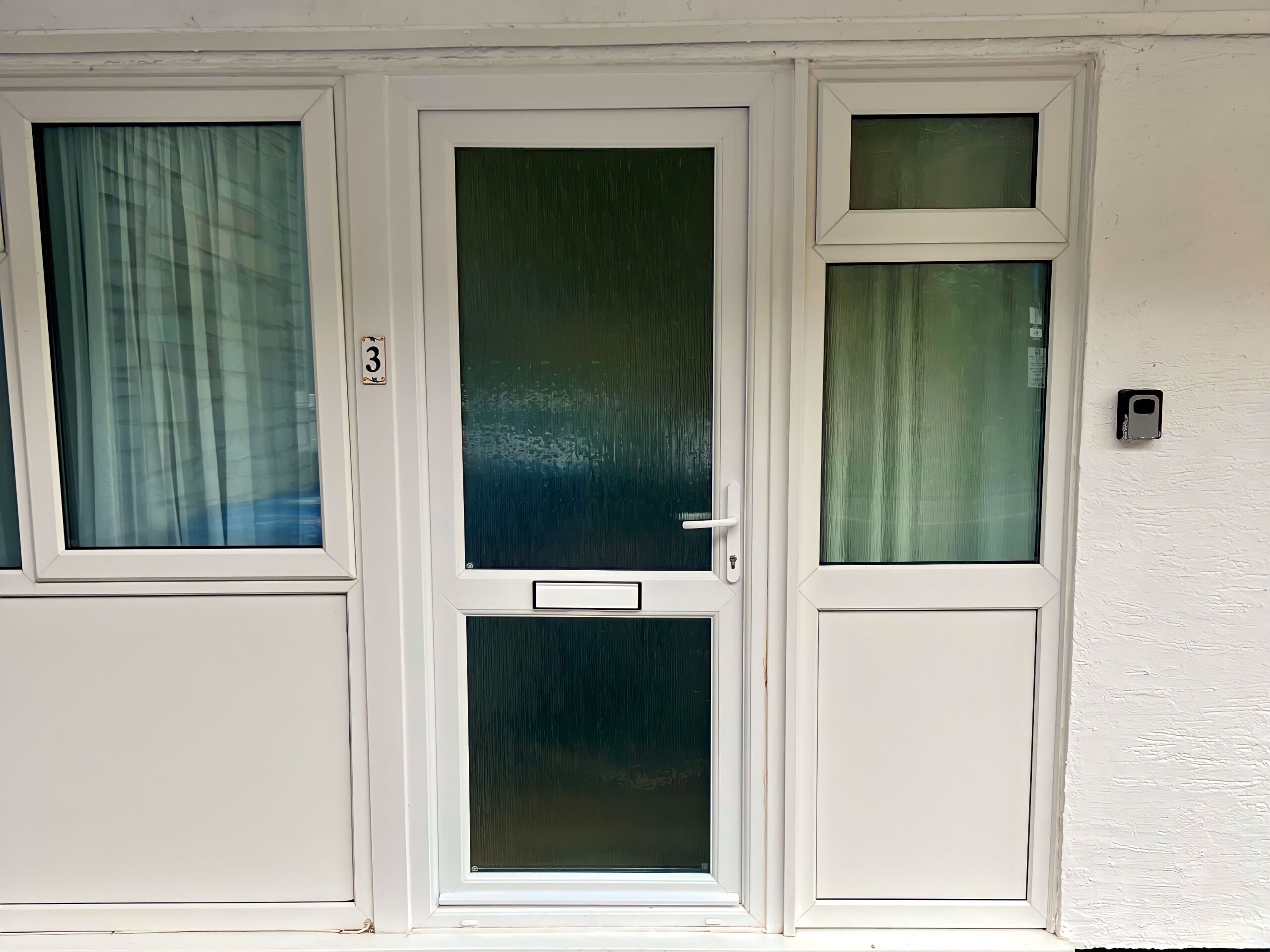 Un ensemble de trois portes à cadre blanc, dotées de panneaux en verre dépoli, chacune étant surmontée d’une plaque numérotée.